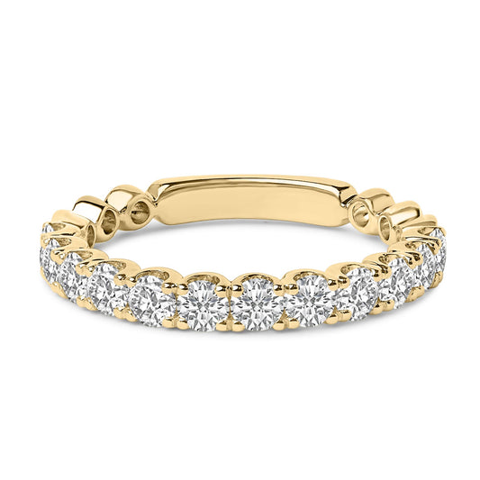 Close-up front angle of a yellow metal ring featuring a continuous row of round white gemstones in four-prong settings.