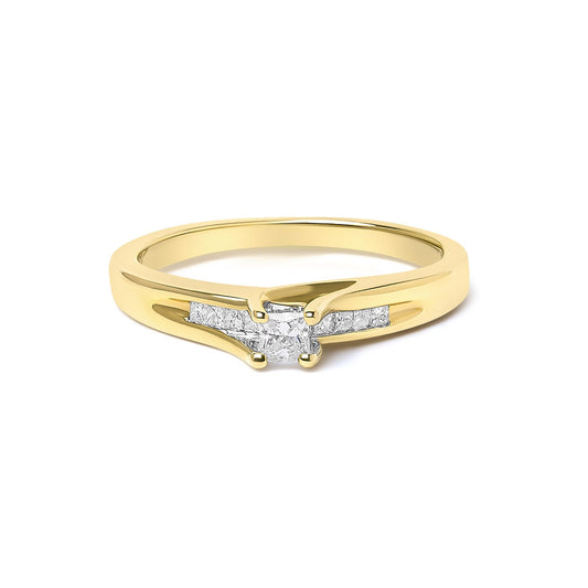 Yellow ring shown at a slight angle with a single princess-shaped white gemstone in a prong setting at the center and additional princess-shaped white gemstones in a channel setting along the band.