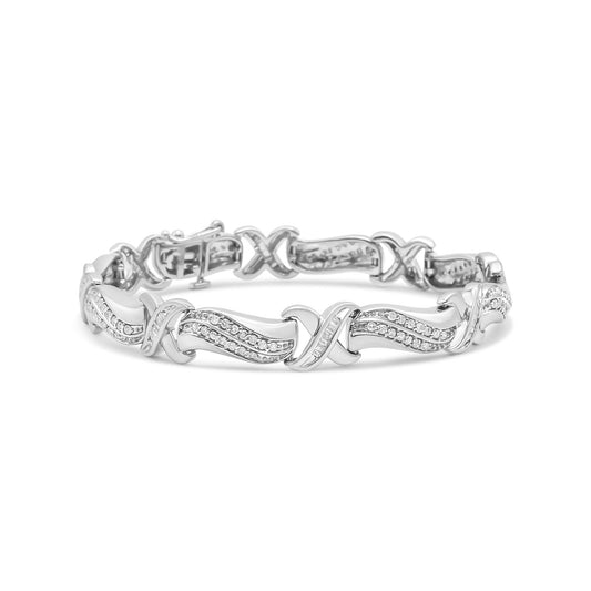 White metal bracelet with crisscross and wave design featuring round and baguette shaped white gemstones, shown from front angle.