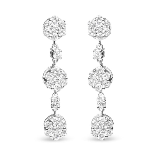 Front view of white metal dangle earrings with clusters of round white gemstones in prong settings.