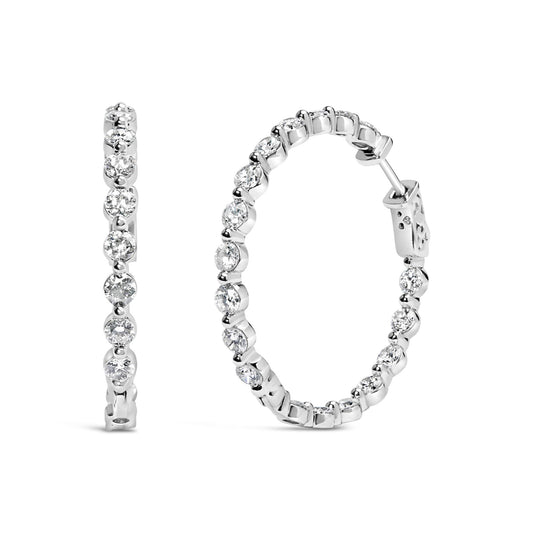 Pair of white metal hoop earrings set with round white gemstones in a 2-prong setting, shown from front and side angles on a white background.