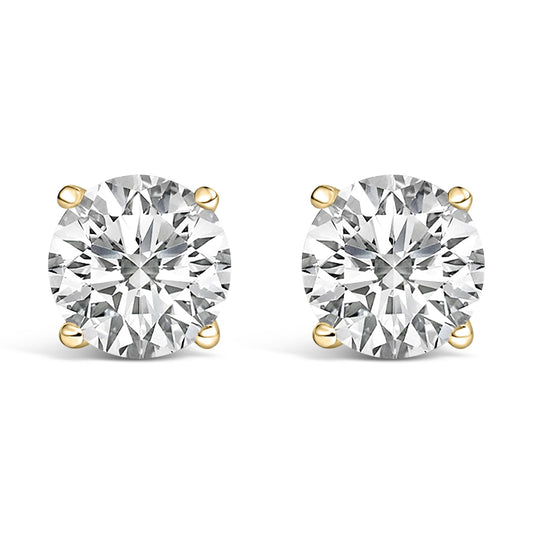 Close-up front view of a pair of yellow metal stud earrings, each featuring a round white gemstone in a four-prong setting.