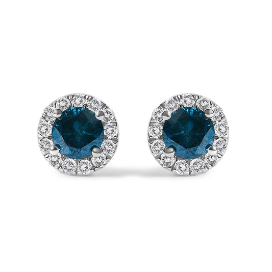 Close-up front angle of a pair of white metal stud earrings featuring a round blue gemstone in a four-prong setting surrounded by smaller round white gemstones in prong settings.