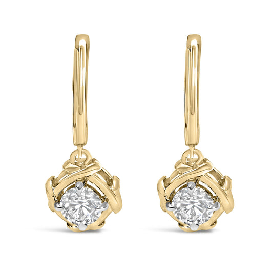 Close-up front view of a pair of yellow metal drop earrings with a round white gemstone in a prong setting at the center.
