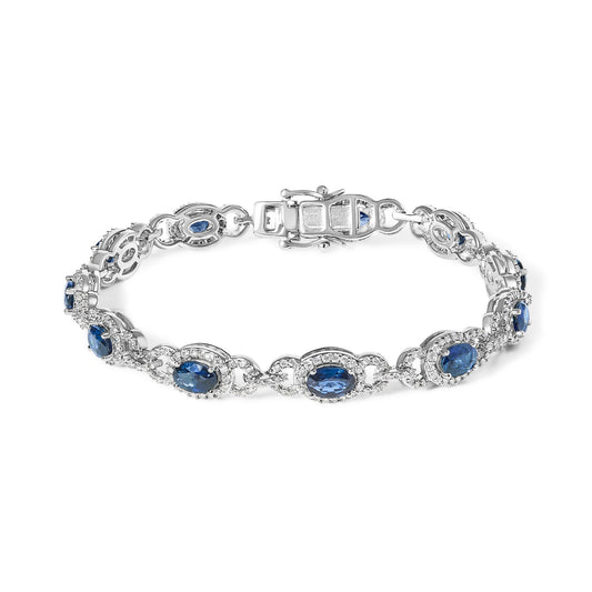White bracelet with oval blue gemstones and round white gemstones in prong settings, shown from a front angle on a white background.