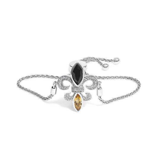 White bracelet with a double chain and a fleur-de-lis design centerpiece featuring a black marquise gemstone at the top, an orange marquise gemstone at the bottom, and pavé set round white gemstones in the design, shown in a front-facing angle on a white background.