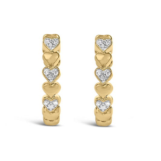Front view of pair of yellow metal hoop earrings decorated with alternating smooth heart shapes and heart shapes featuring pave-set white gemstones.