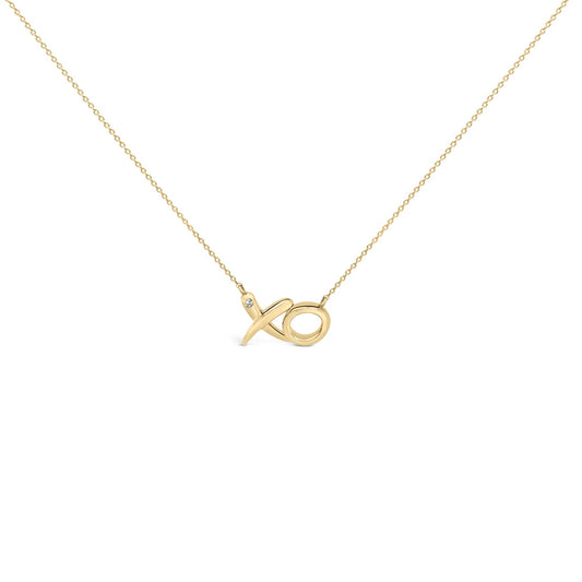 Yellow metal necklace with an XO pendant featuring a round white gemstone in a bezel setting, shown in a front angled close-up shot.
