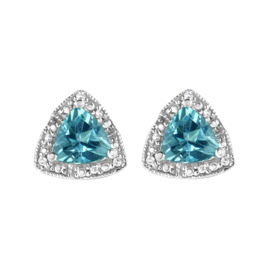 Front view of white metal earrings with blue trillion-shaped gemstones surrounded by round white gemstones in prong settings.