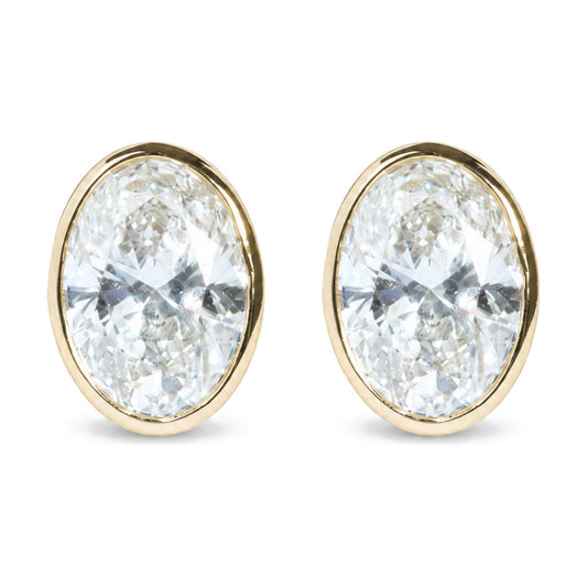 Close-up front view of a pair of yellow metal earrings each featuring a large oval-shaped white gemstone in a bezel setting.