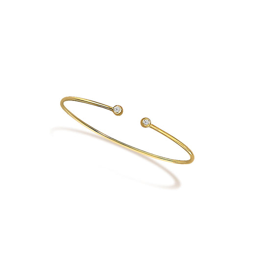Open yellow metal bracelet with round white gemstones in bezel settings at each end, shown at a slight angle.