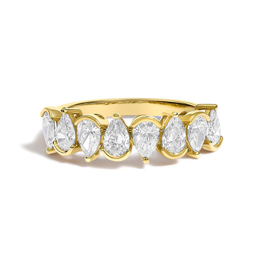 Close-up angled side view of a yellow metal ring featuring a continuous row of pear-shaped white gemstones in bezel settings around the band.