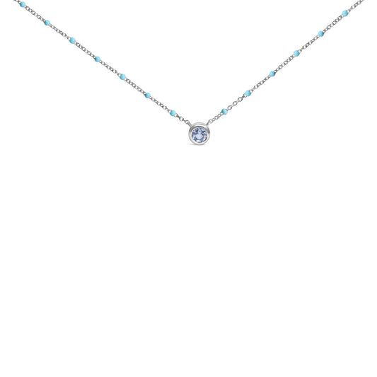 White necklace with small blue beads along the chain and a single round blue gemstone in a bezel setting at the center, shown in a front-facing close-up shot on a white background.