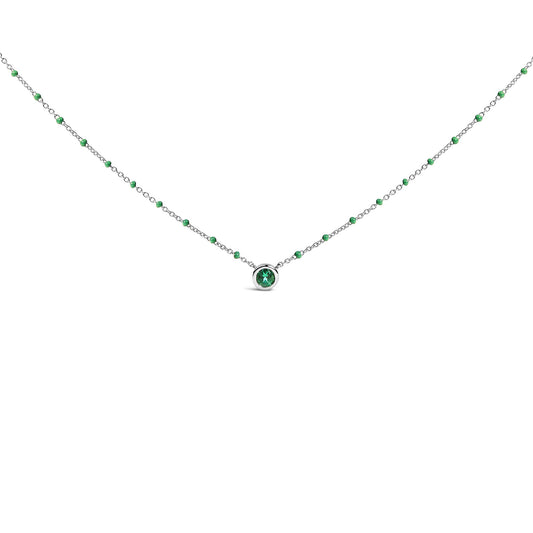 White necklace with small round green gemstones evenly spaced along the chain and a single bezel-set round green gemstone pendant, shown in a front-facing close-up angle.