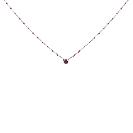 Front view of a white metal necklace featuring a round red gemstone in a bezel setting at the center, with small red beads spaced along the chain.