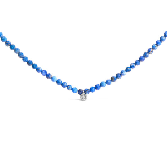 Front angle close-up of a white metal necklace with small round blue gemstones and a single round white gemstone pendant in the center.