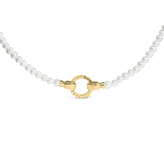 Close-up front angle of a yellow metal and white round bead necklace featuring a circular yellow metal clasp.