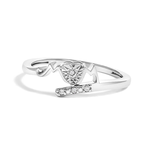 White metal ring with a heart-shaped design and round white gemstones in prong settings, photographed at a slight angle.