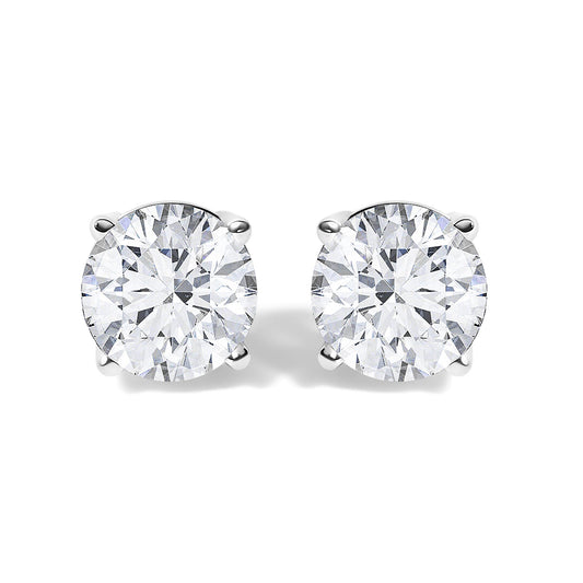 Front view of a pair of white metal stud earrings each with a round white gemstone in a four-prong setting.