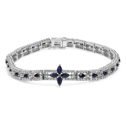 White metal bracelet with marquise-shaped blue gemstones arranged in a floral pattern and surrounded by round white gemstones, shown from a front angled view.