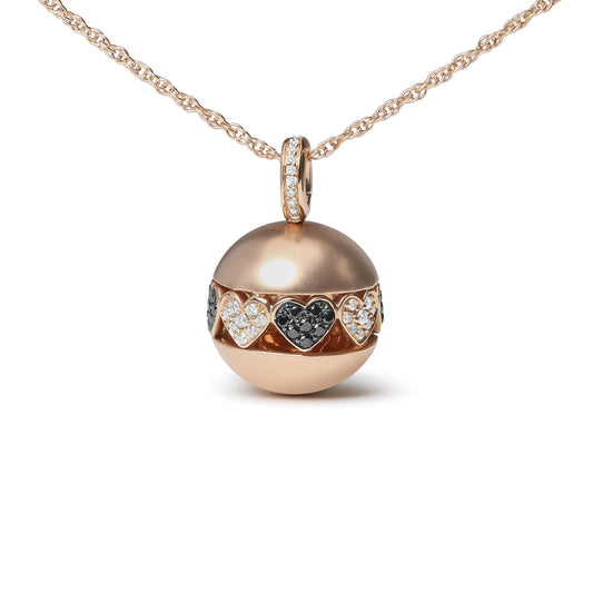 Front-facing shot of a rose metal necklace with a spherical pendant featuring alternating heart shapes set with black and white round prong-set gemstones, hanging on a matching chain.